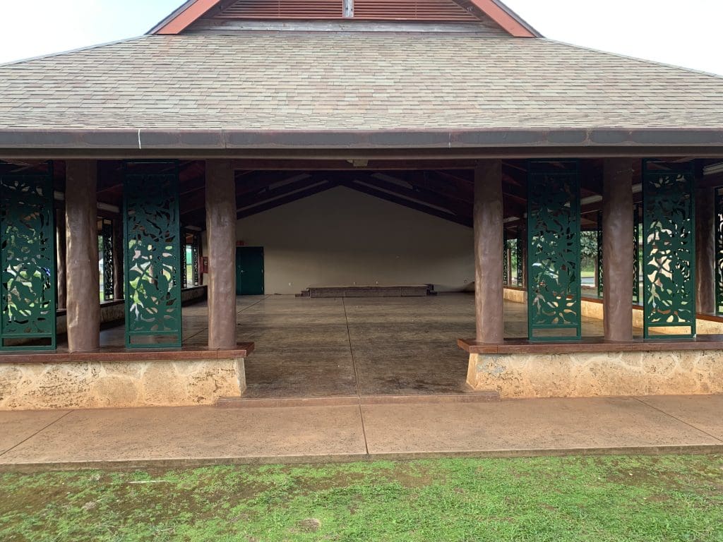 A large building with a porch and grass in the foreground.